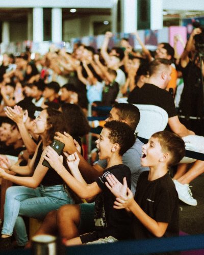 Enthusiastic crowd cheering at indoor event, capturing vibrant energy.